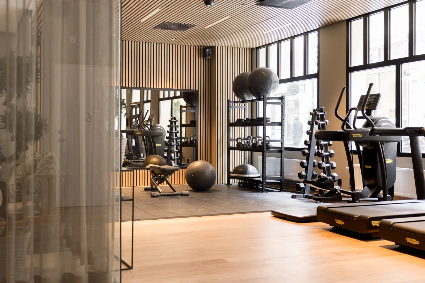 The gym floor at Elite Hotel Adlon with free weights and cardio equipment
